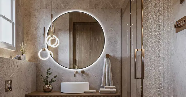 Backlit round mirror above a washbasin in a stone bathroom